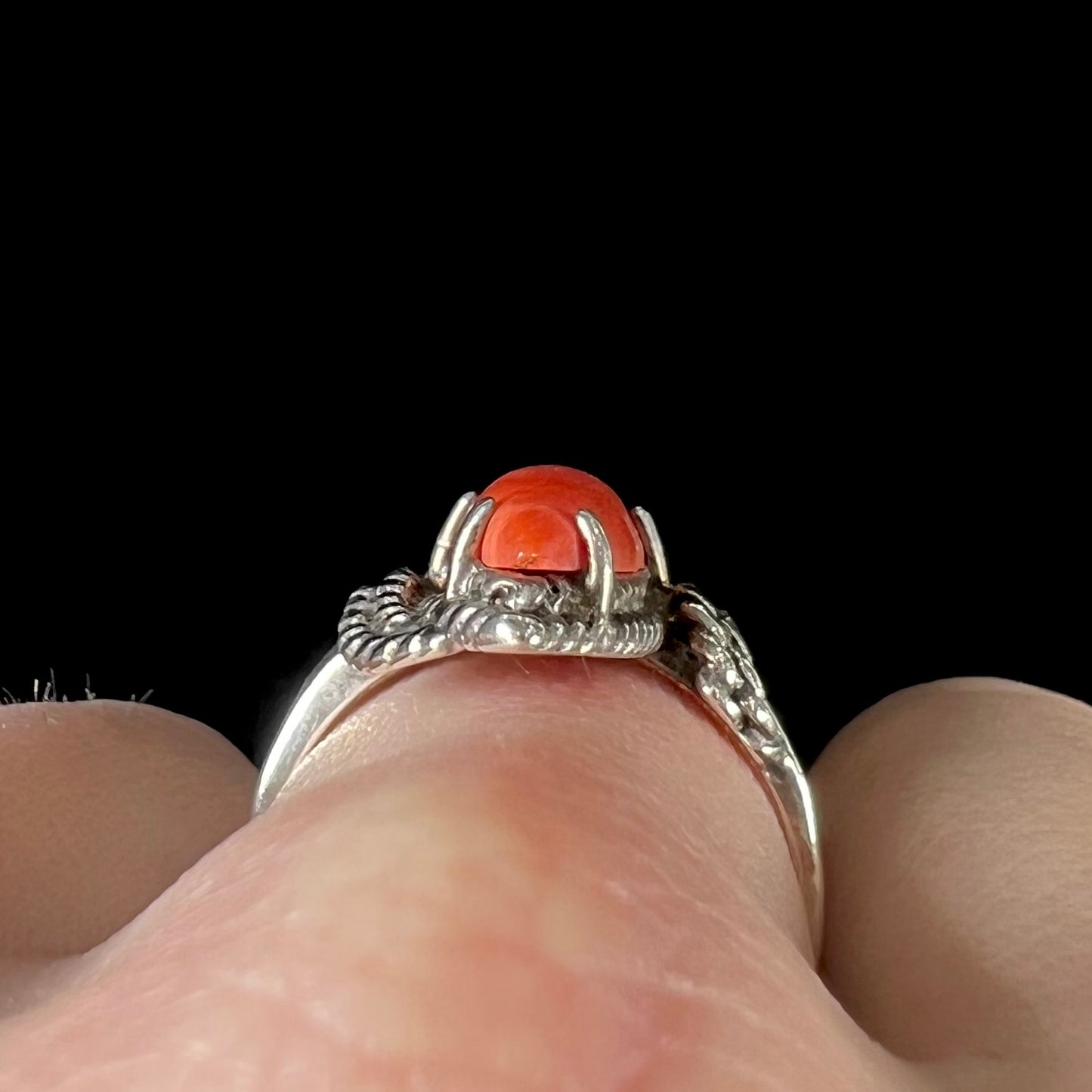 A prong-set silver ring set with a red marquise cut coral.