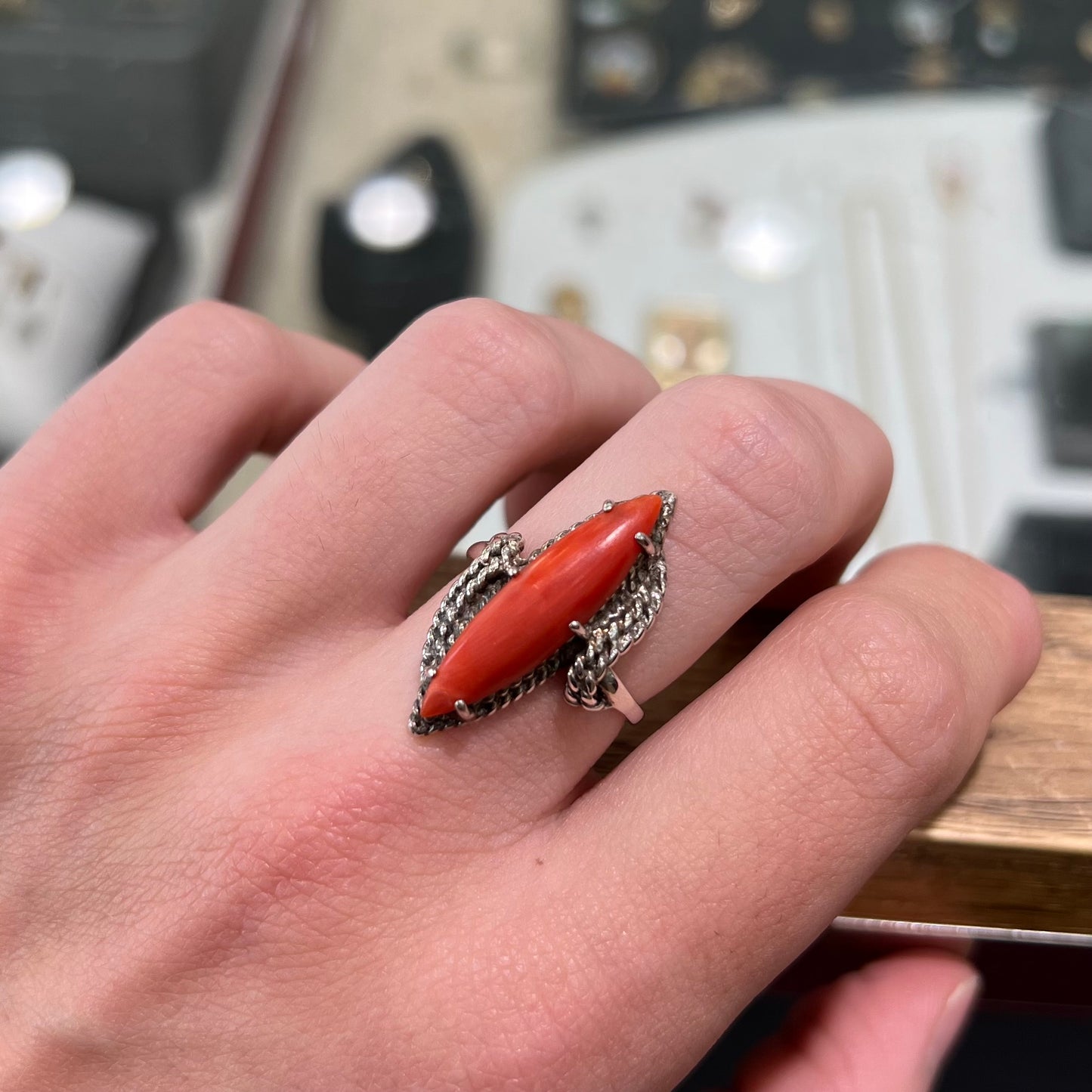 A prong-set silver ring set with a red marquise cut coral.