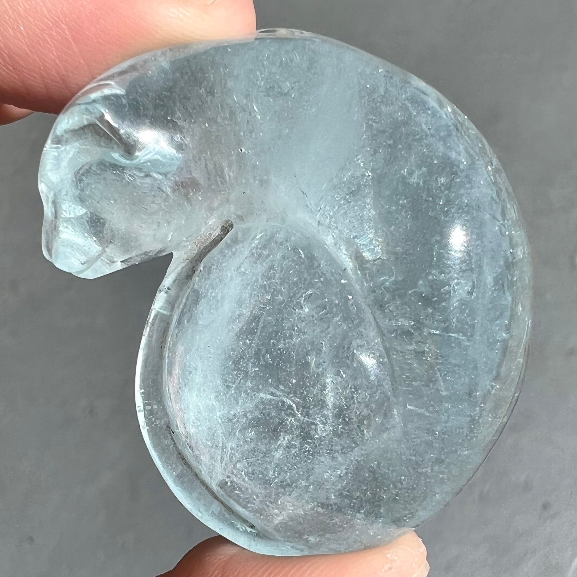 A stone cat carved from a sky blue topaz crystal.