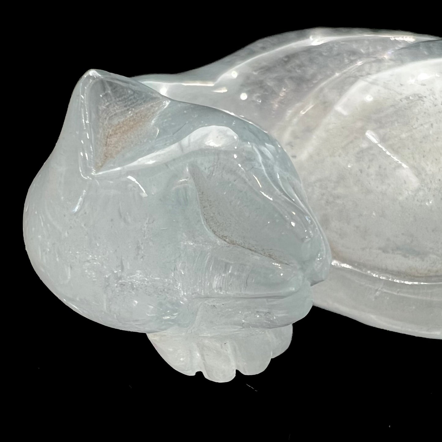 A stone cat carved from a sky blue topaz crystal.