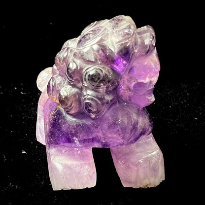 A stone foo dog carving carved from a purple Brazilian amethyst crystal.