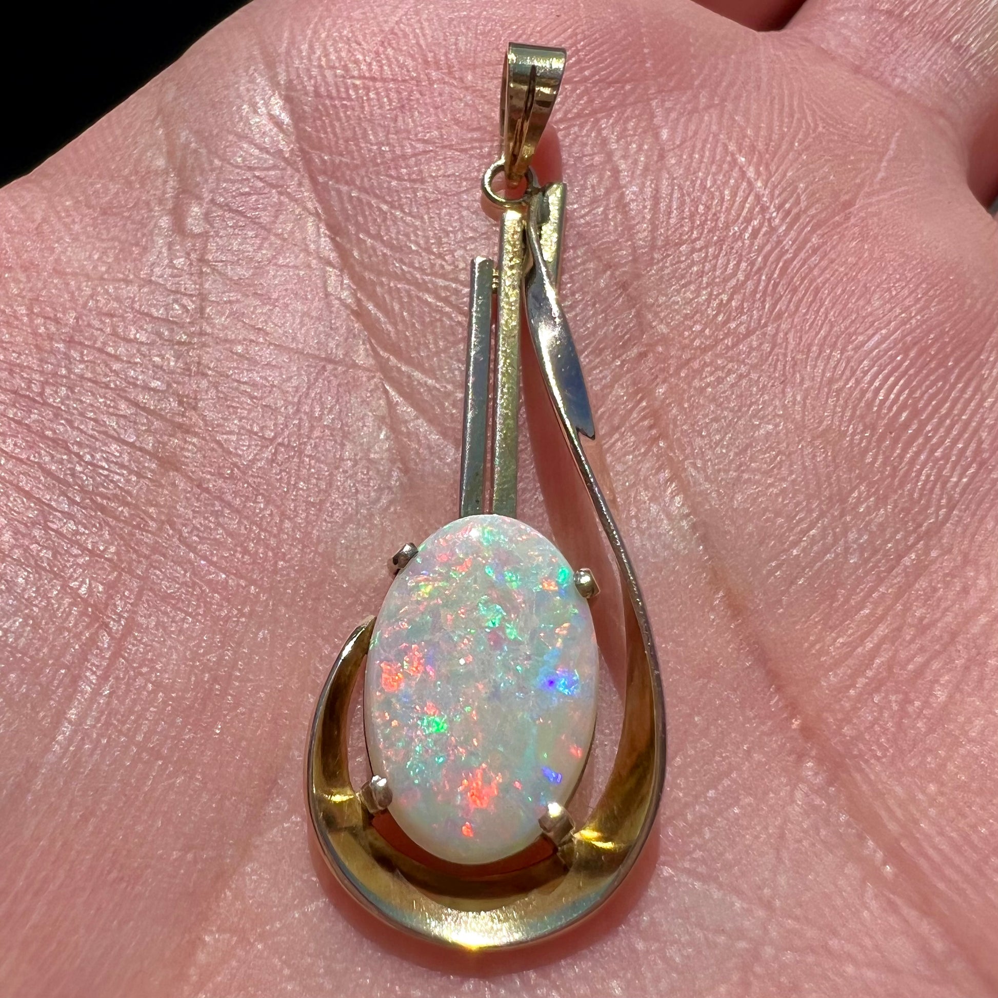 A handmade gold drop pendant set with an oval cabochon cut white crystal opal.