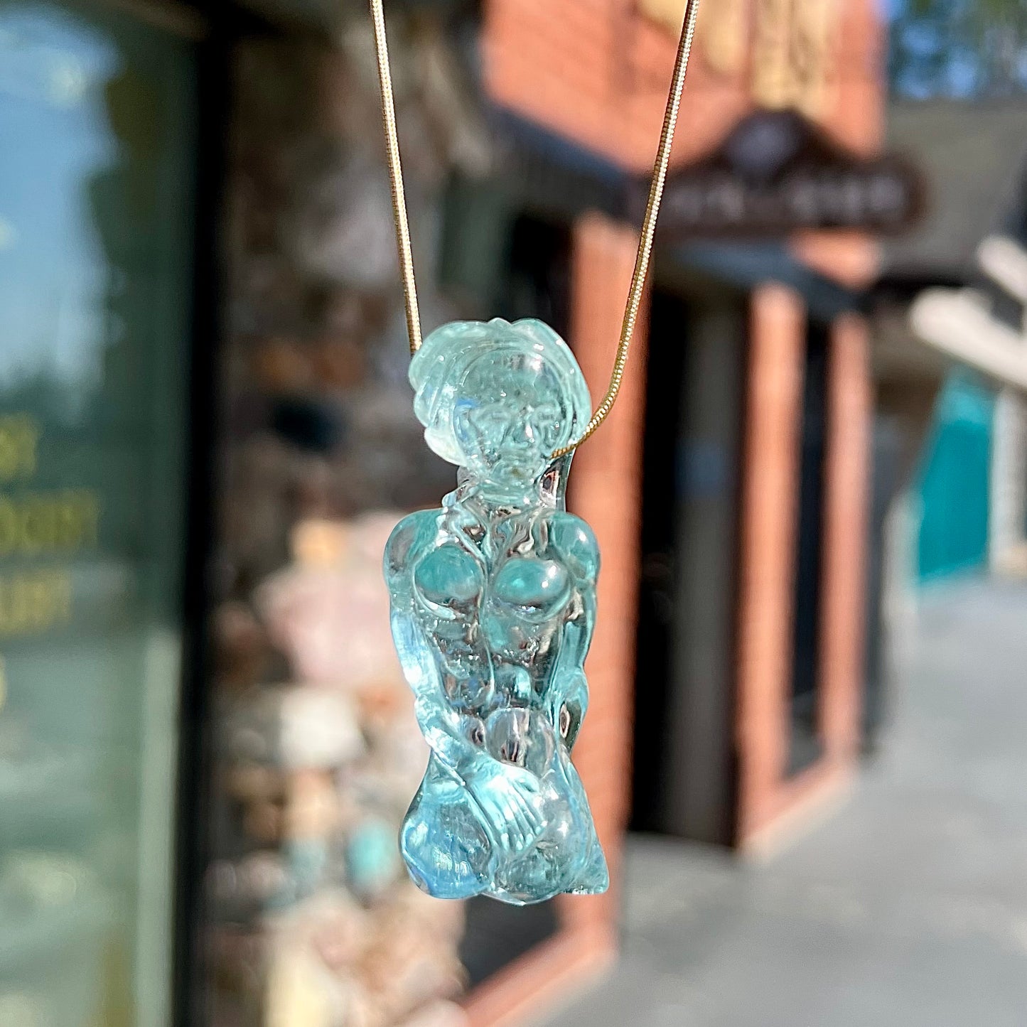 A stone woman figure carved from a blue aquamarine crystal.  The piece resembles Venus Gummi de Milo.