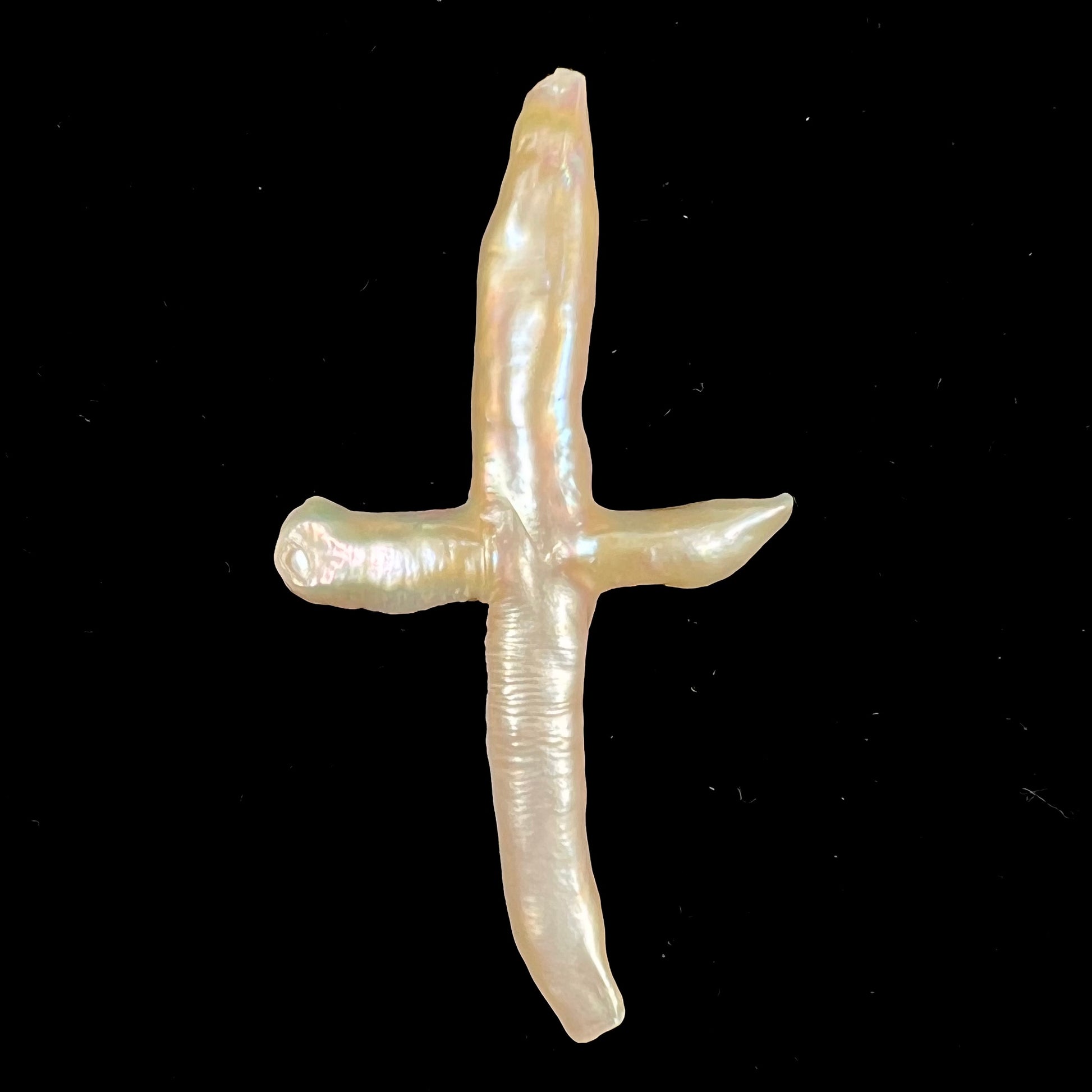 A loose, cultured dark cream colored freshwater pearl cross with pink overtones.