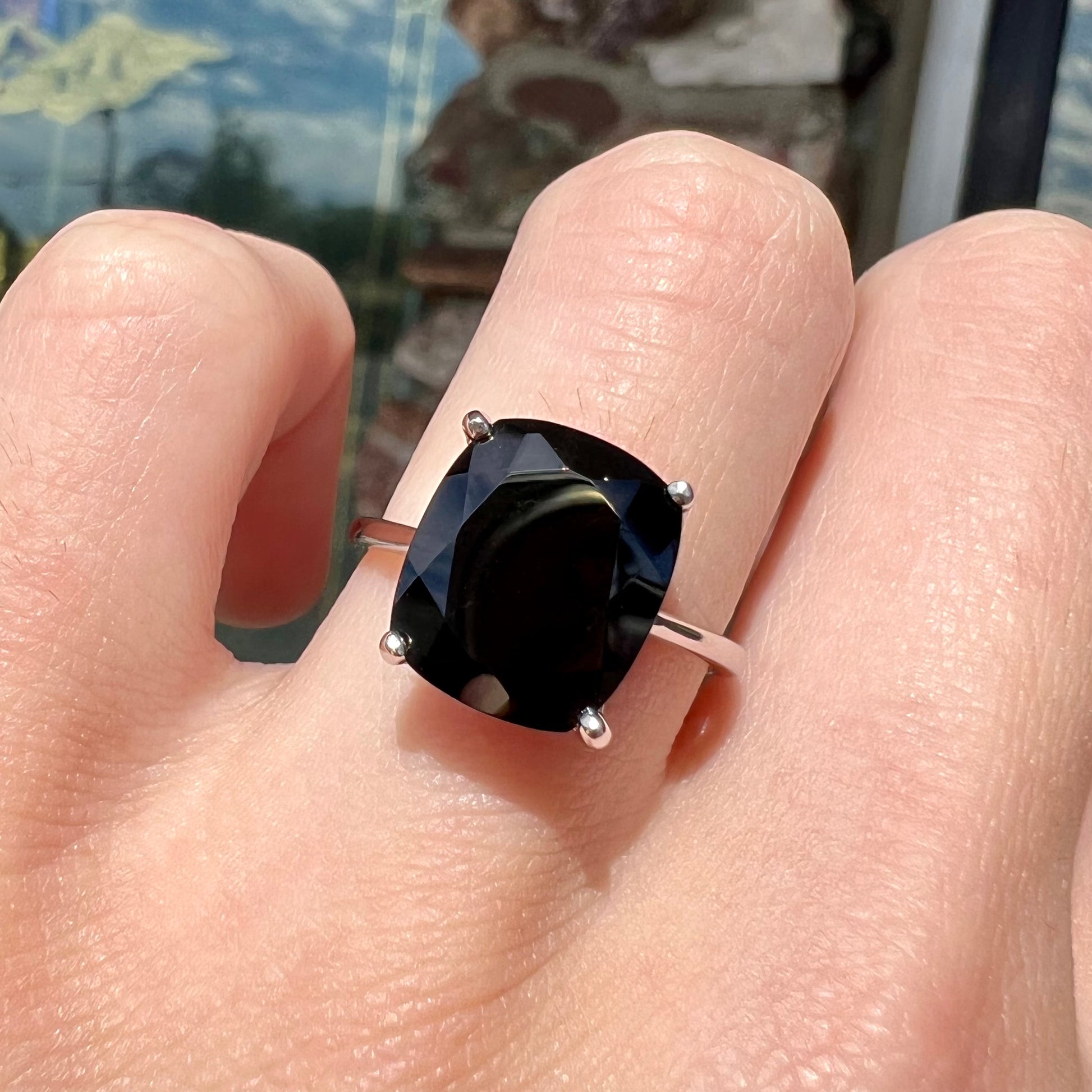 A cushion cut black spinel prong set in a sterling silver solitaire ring.