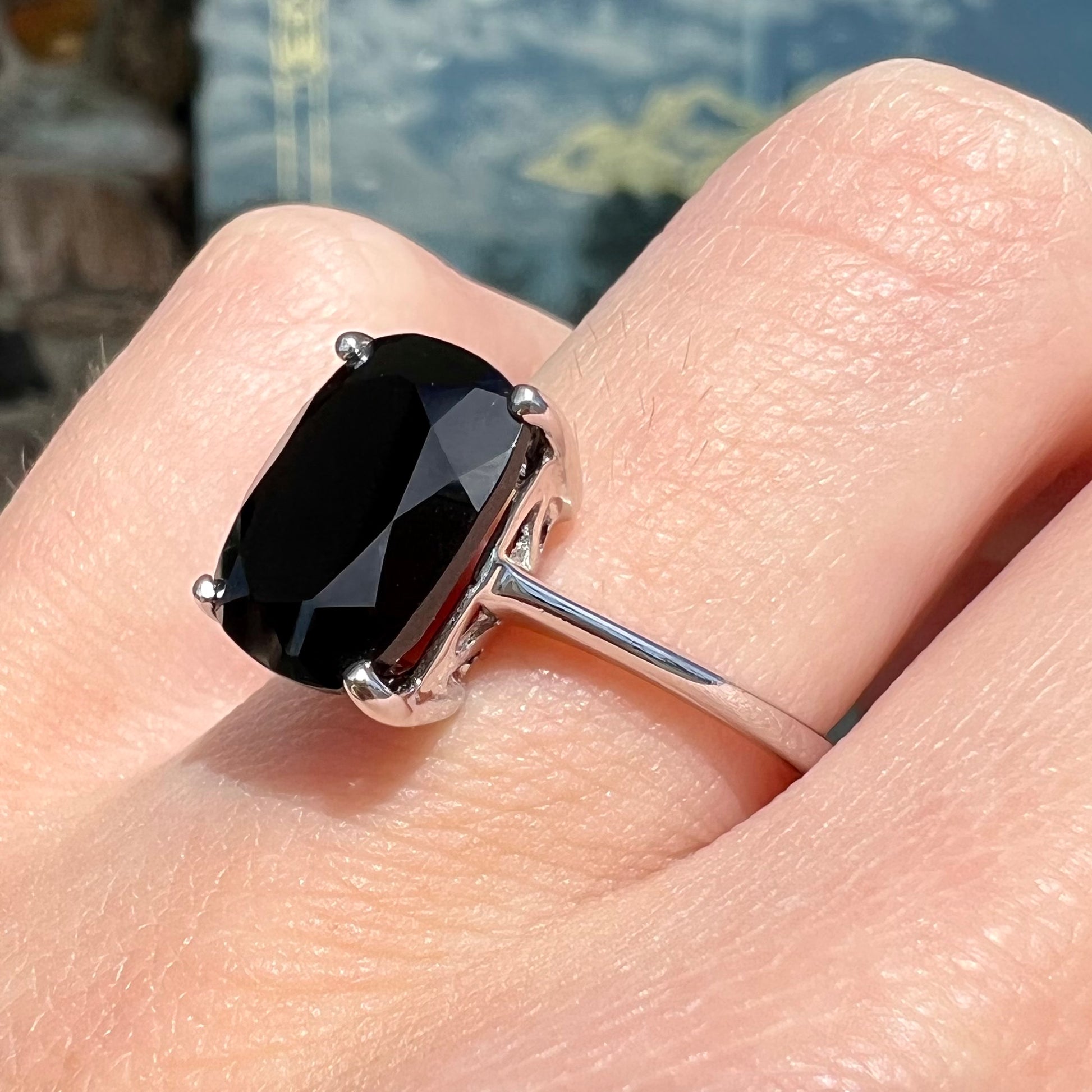 A cushion cut black spinel prong set in a sterling silver solitaire ring.