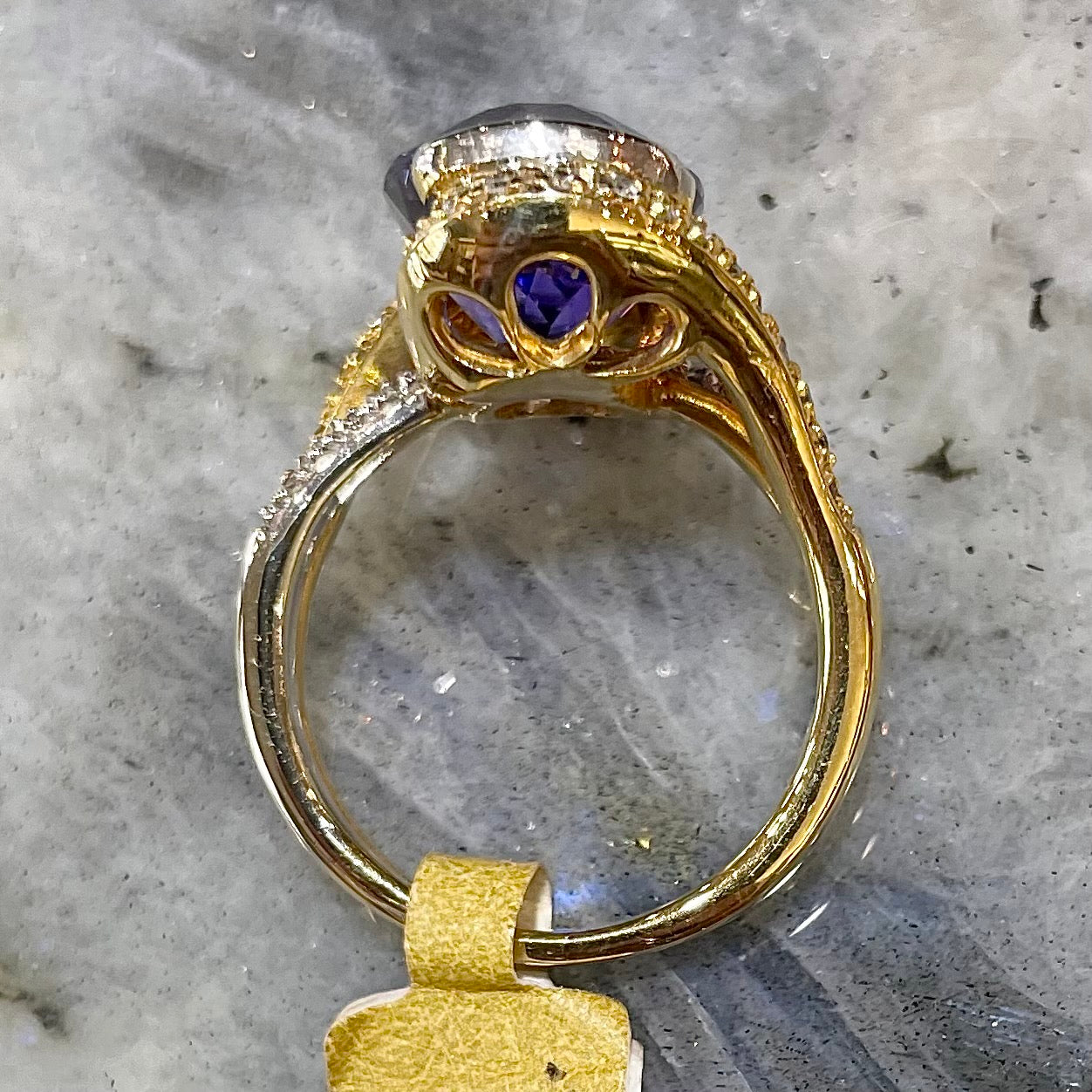 A large, oval cut blue tanzanite set in a two tone yellow and white gold diamond ring.