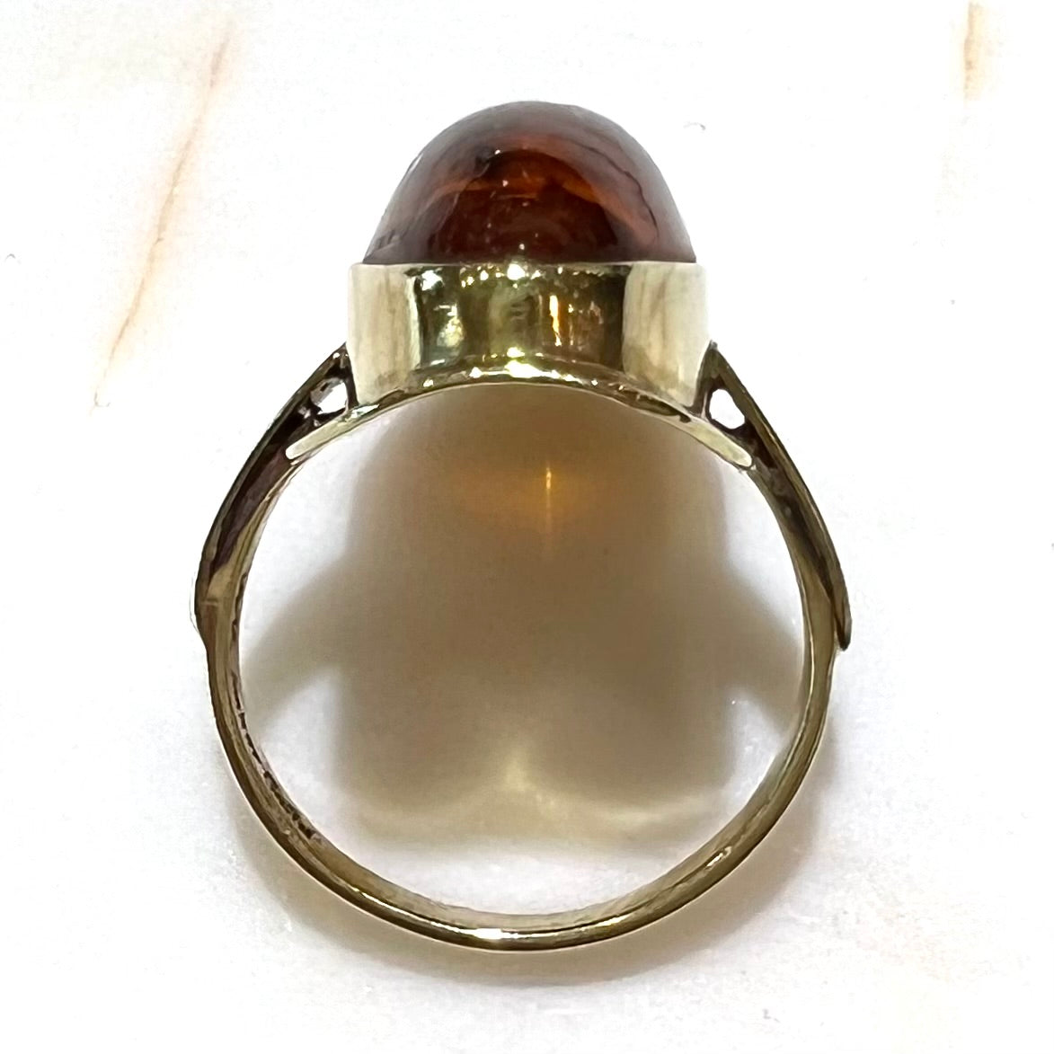 An oval cabochon cut Baltic amber stone set in a yellow gold ring and stamped "AMBER GUILD."