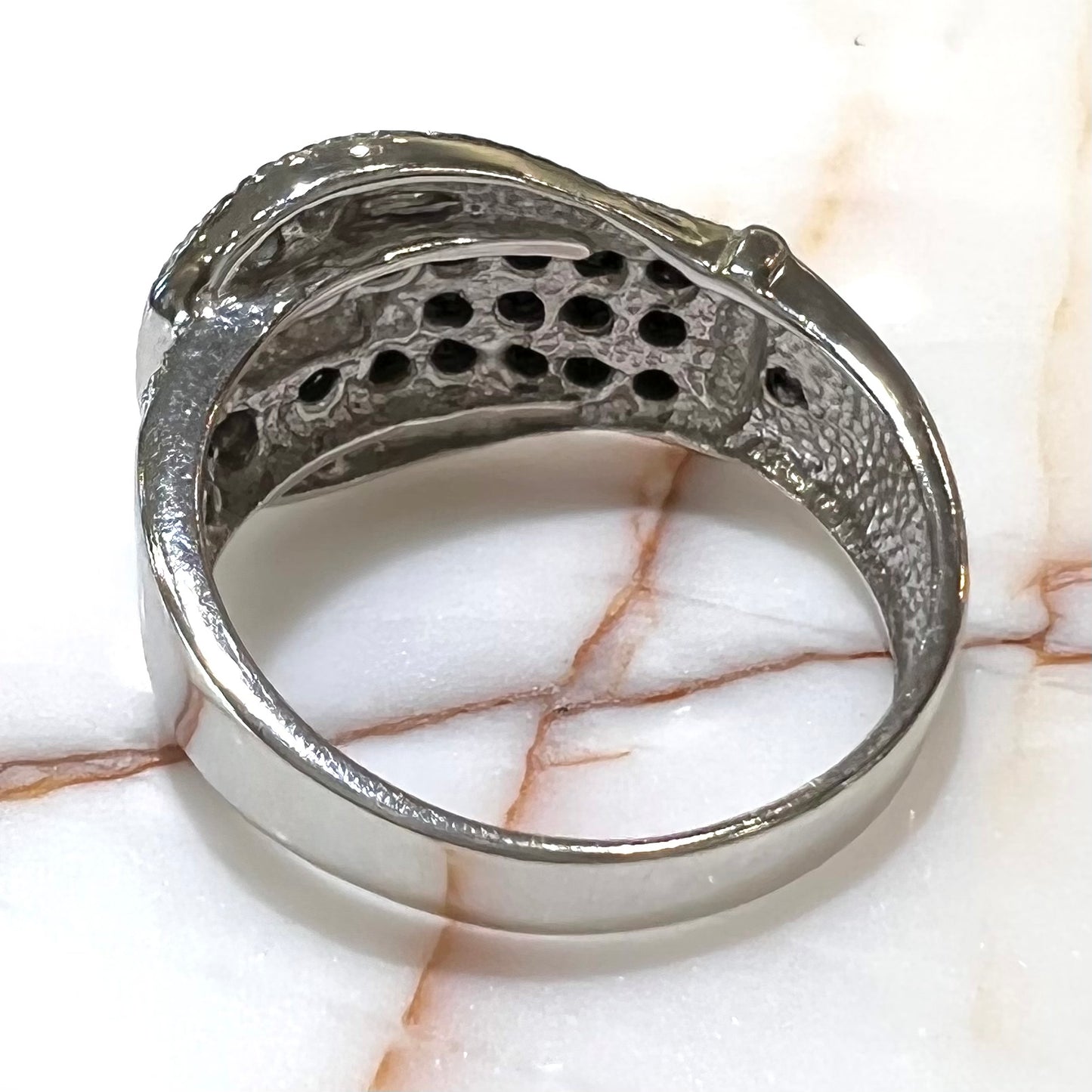 A white gold buckle ring pave set with round black and white diamonds.