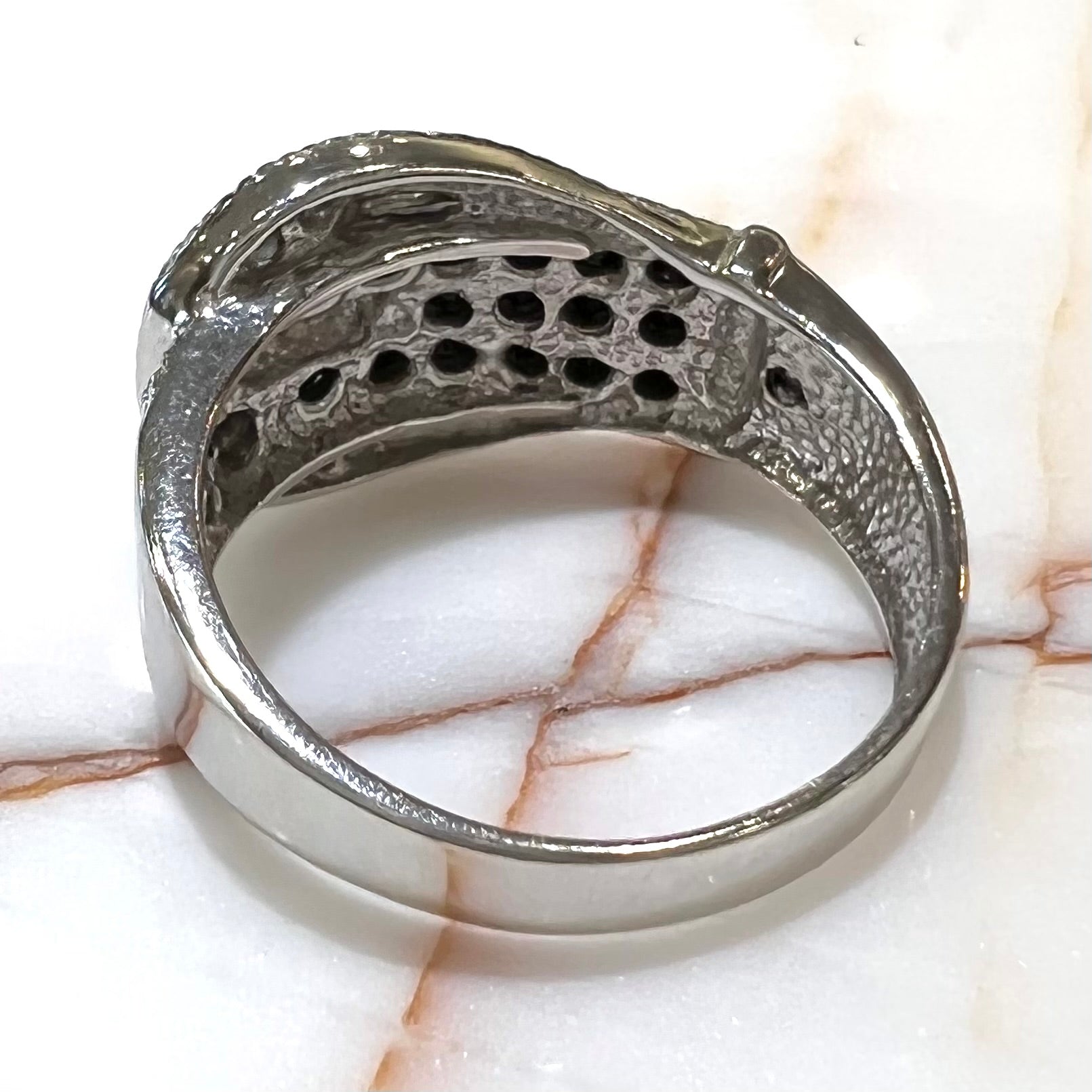 A white gold buckle ring pave set with round black and white diamonds.