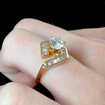 A gold diamond ring set with a round cut center stone with channel set baguette cut accent stones.