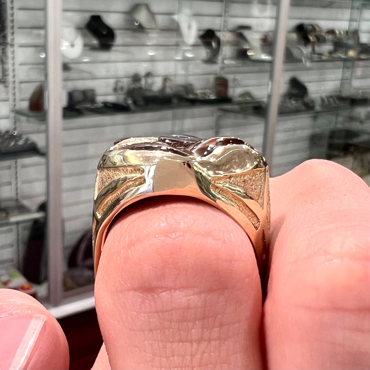 A yellow gold men's thug ring set with four fire agate stones resembling a spooky face.