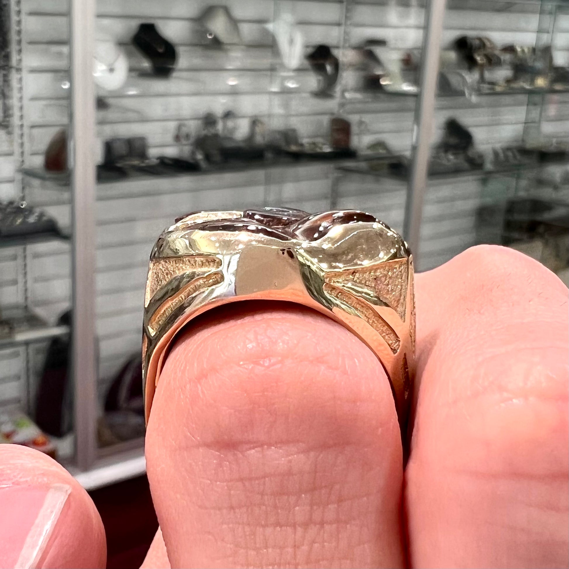 A yellow gold men's thug ring set with four fire agate stones resembling a spooky face.