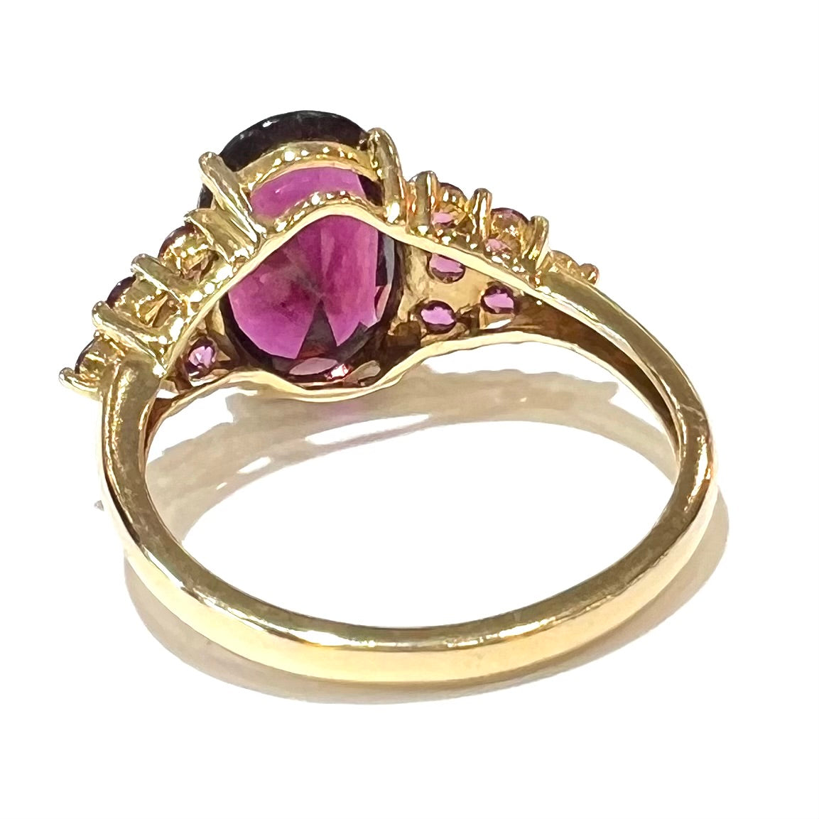 A yellow gold ring set with clusters of purple garnets set on each side of a rhodolite garnet.