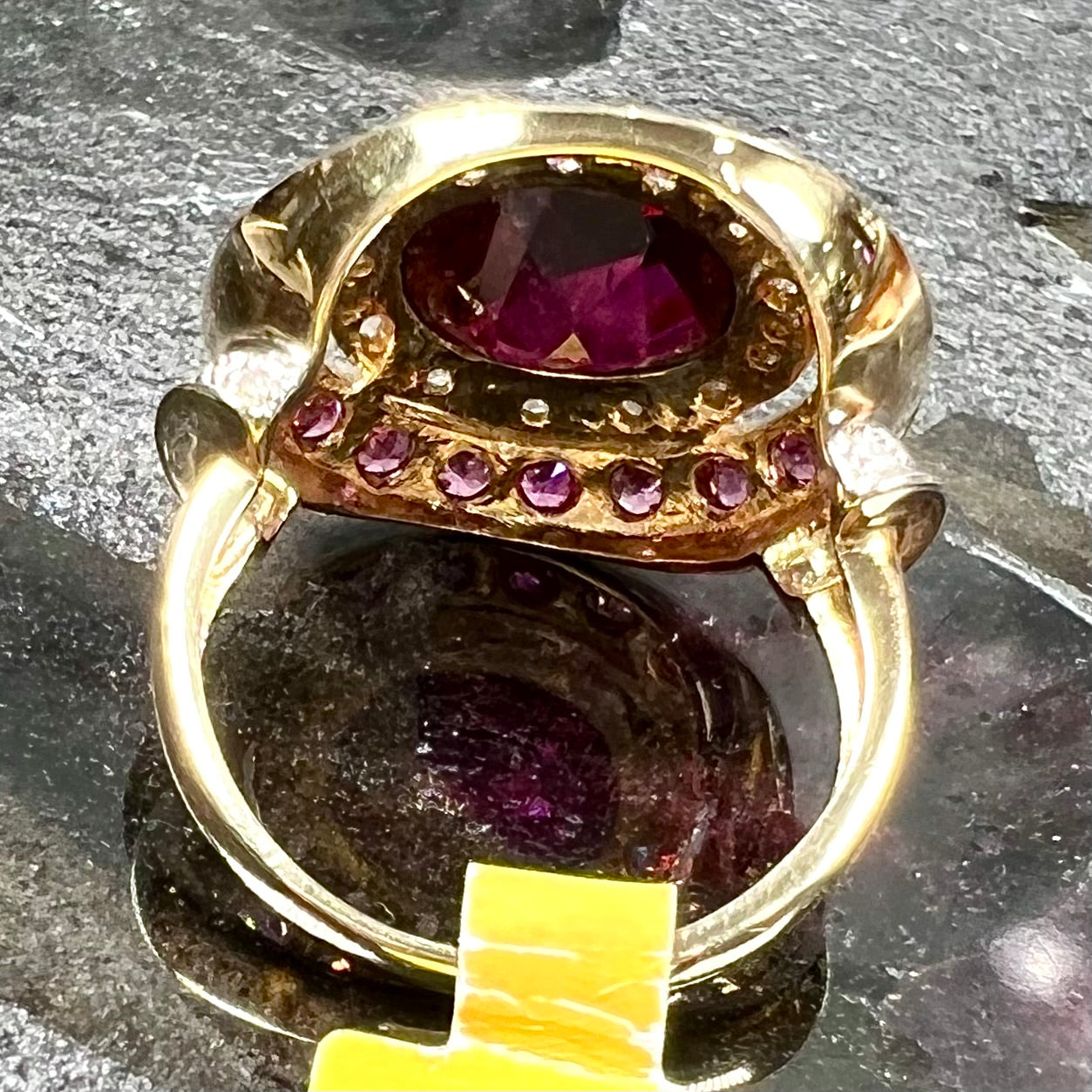 A yellow gold garnet and diamond halo ring set with a checkerboard cut rhodolite garnet center stone.