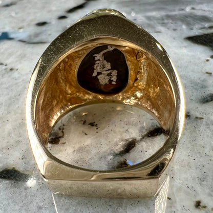 A solid, yellow gold men's fire agate ring.  The predominant color is red with green undertones.