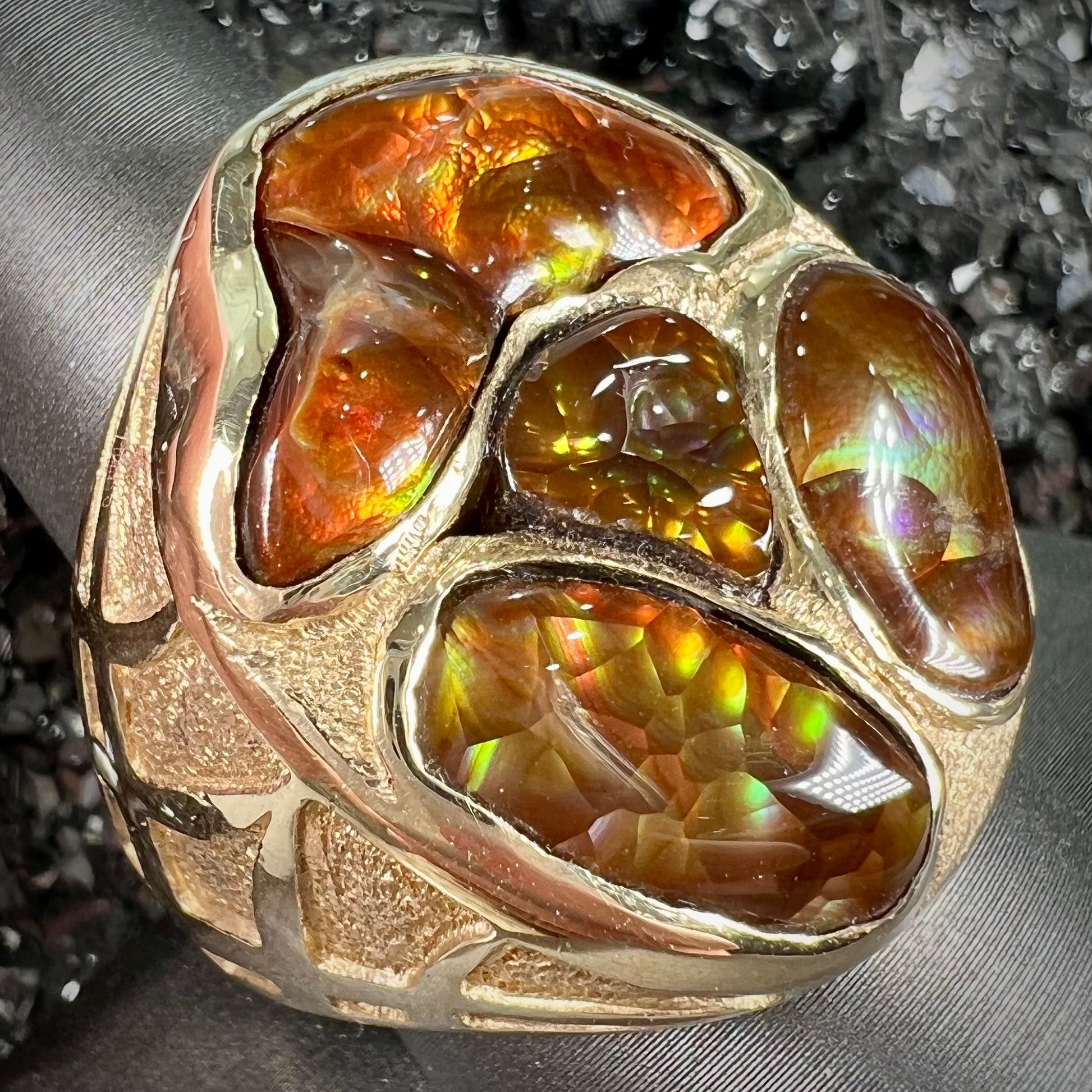 A yellow gold men's thug ring set with four fire agate stones resembling a spooky face.