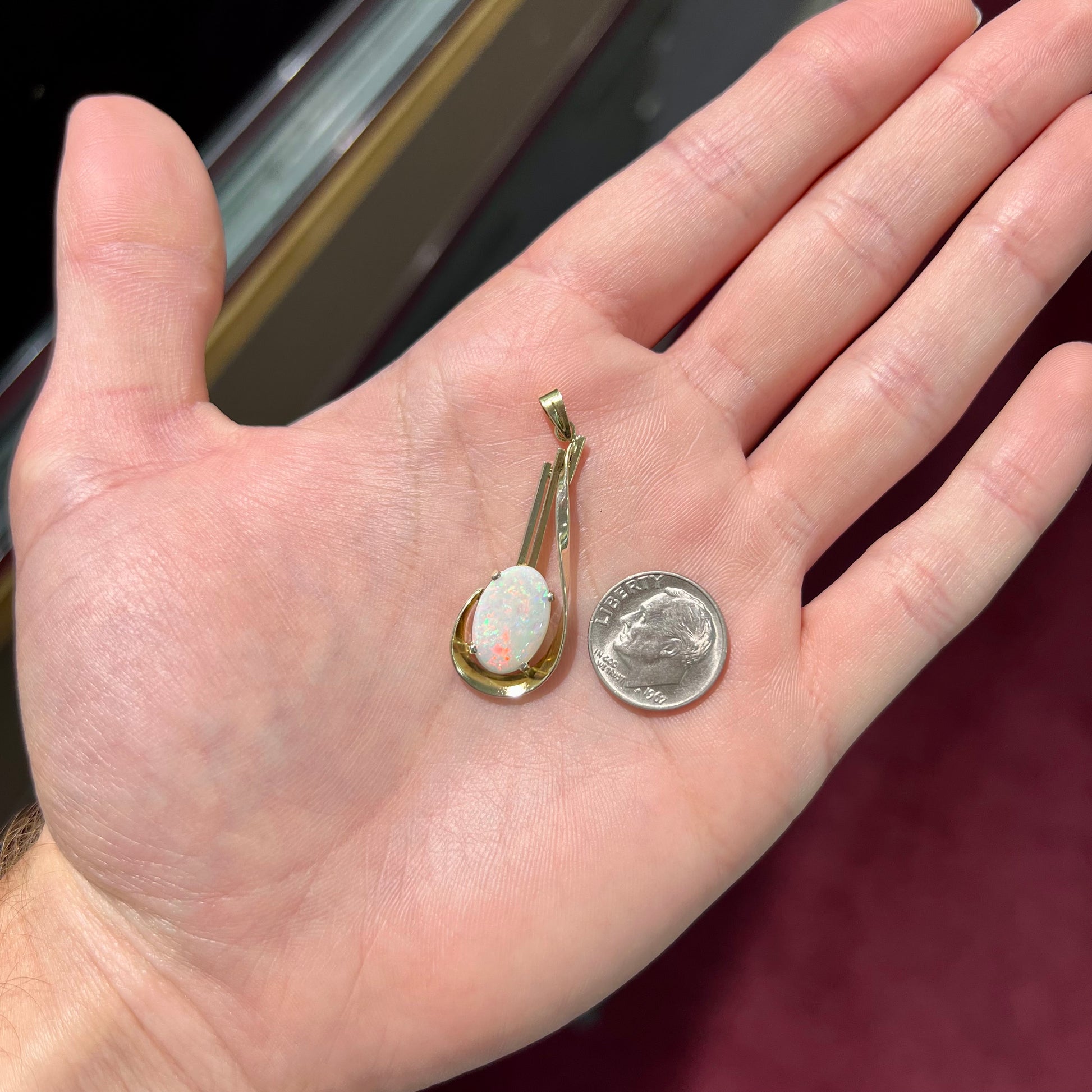 A handmade gold drop pendant set with an oval cabochon cut white crystal opal.