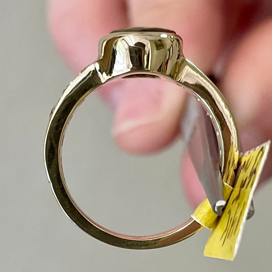 A ladies' oval cabochon cut fire agate and diamond engagement ring cast in yellow gold.