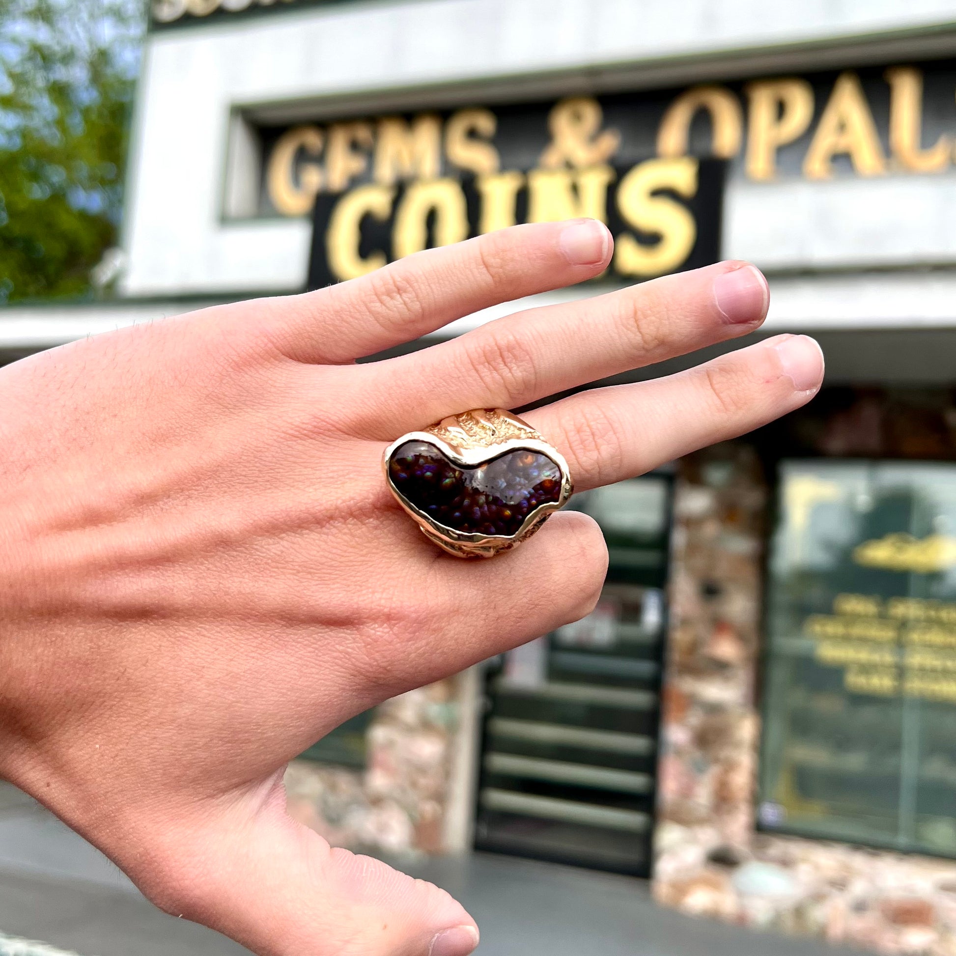 A men's Deer Creek fire agate solitaire ring cast in yellow gold.  The stone is predominantly purple.