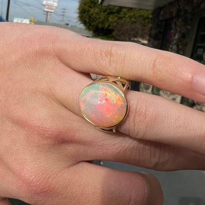 A custom yellow gold men's ring set with two diamonds and a large oval cabochon cut opal from Ethiopia, Africa.