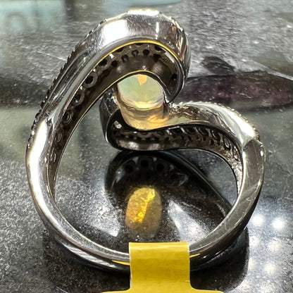 A sterling silver ring set with round black spinel stones and an oval cut, faceted Ethiopian opal.