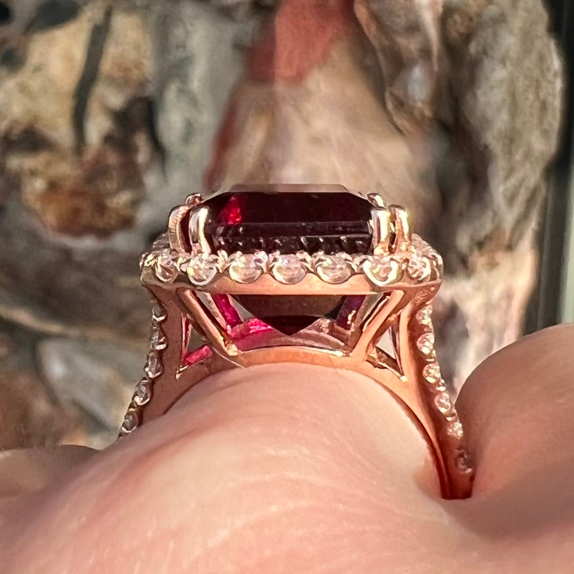 Red emerald cut rubellite tourmaline gemstone set with near flawless round cut diamonds in rose gold.