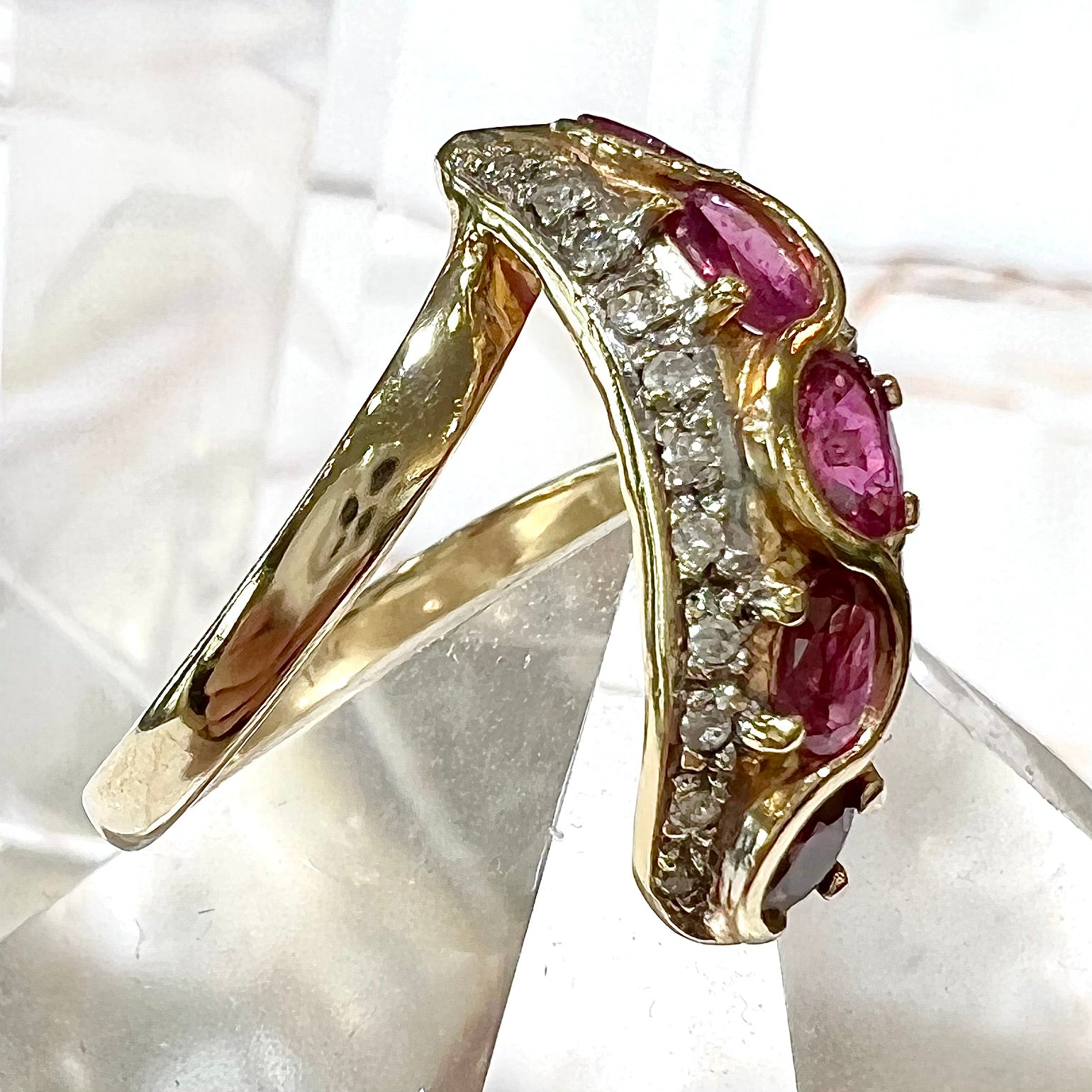 A custom freeform design yellow gold twisted shank ring set with five oval cut rubies and small round diamonds.