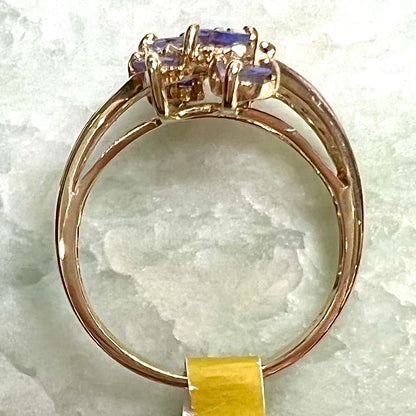 A pear shape tanzanite cluster ring channel set with diamonds in yellow gold.