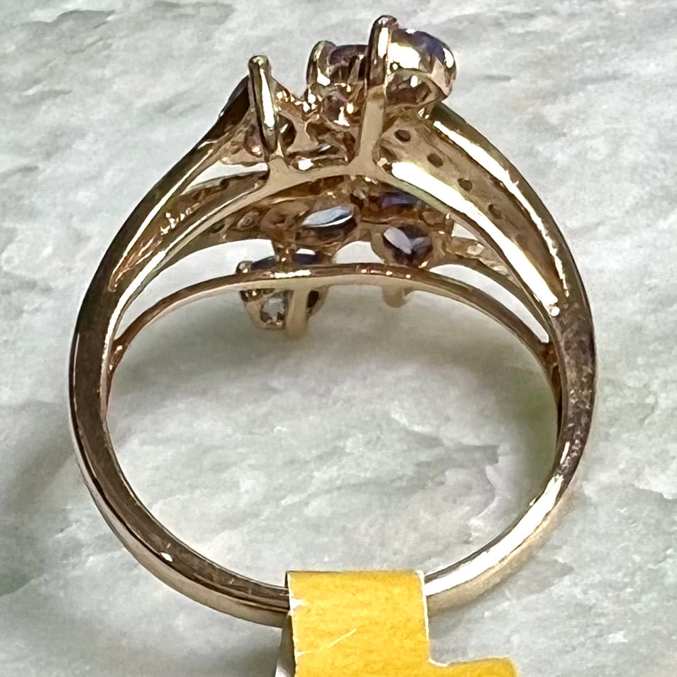 A pear shape tanzanite cluster ring channel set with diamonds in yellow gold.