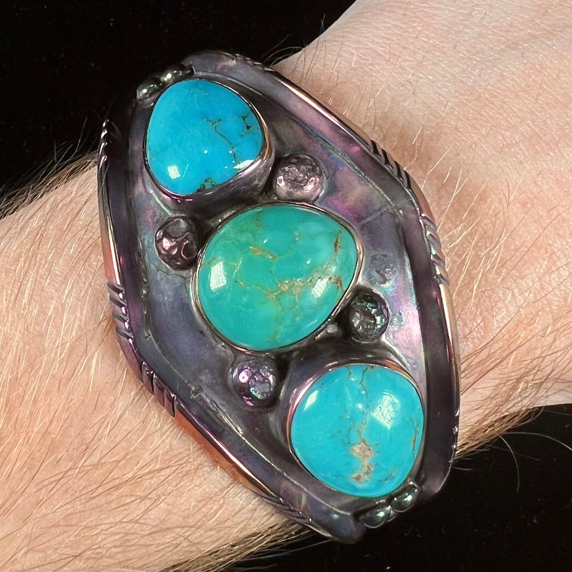 A men's Navajo three stone turquoise cuff bracelet handmade by artist, Dean Brown.  The silver has an iridescent purple patina.