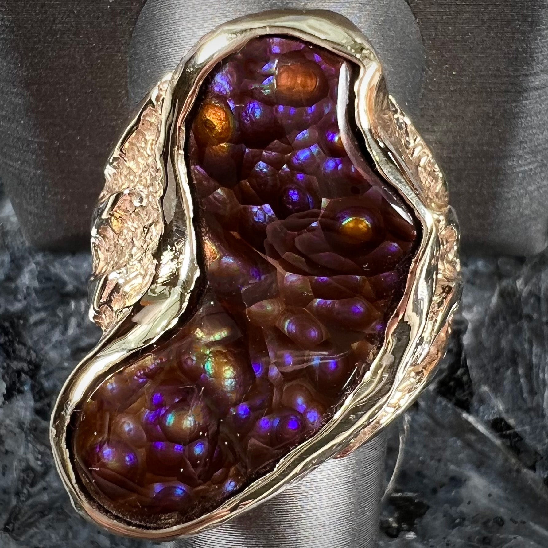 A men's Deer Creek fire agate solitaire ring cast in yellow gold.  The stone is predominantly purple.
