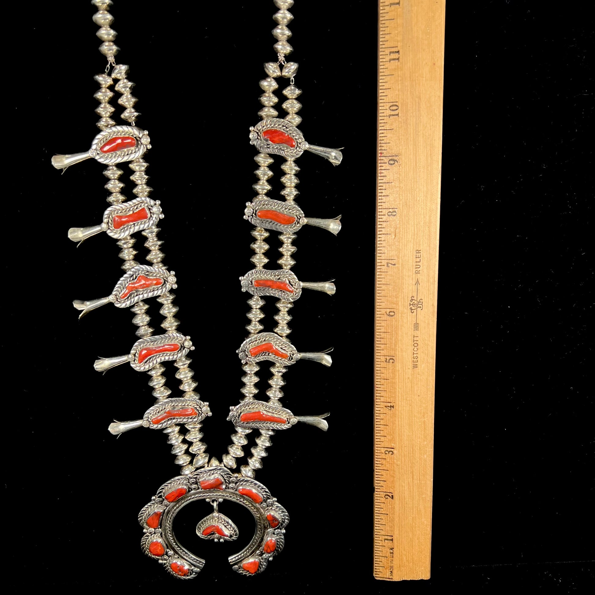 A Navajo style squash blossom necklace set with red coral branches, handmade by artist Delbert Chatter.