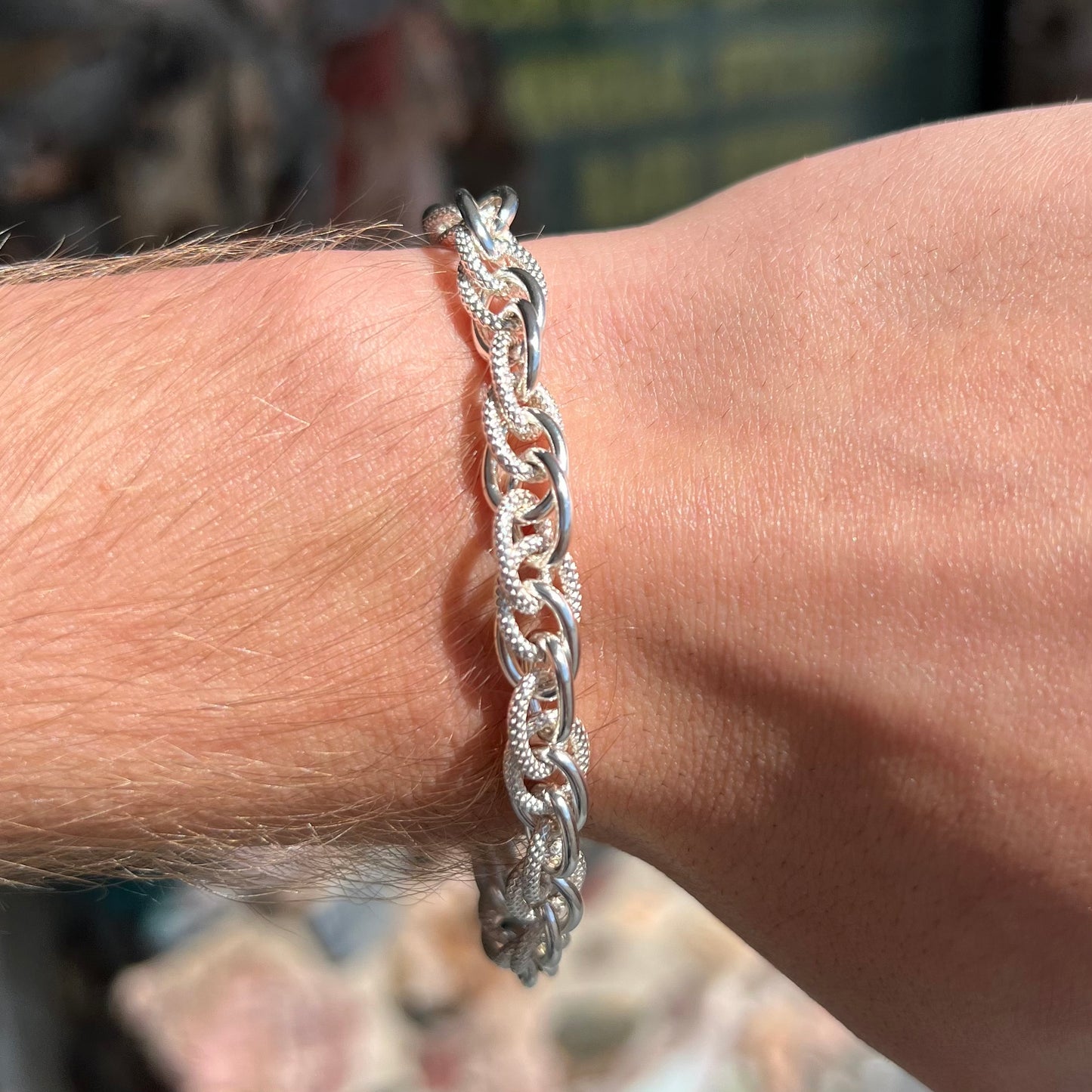 A silver toggle clasp link bracelet.  Some of the links are textured, and others are polished.  The toggle ring is stamped "India."