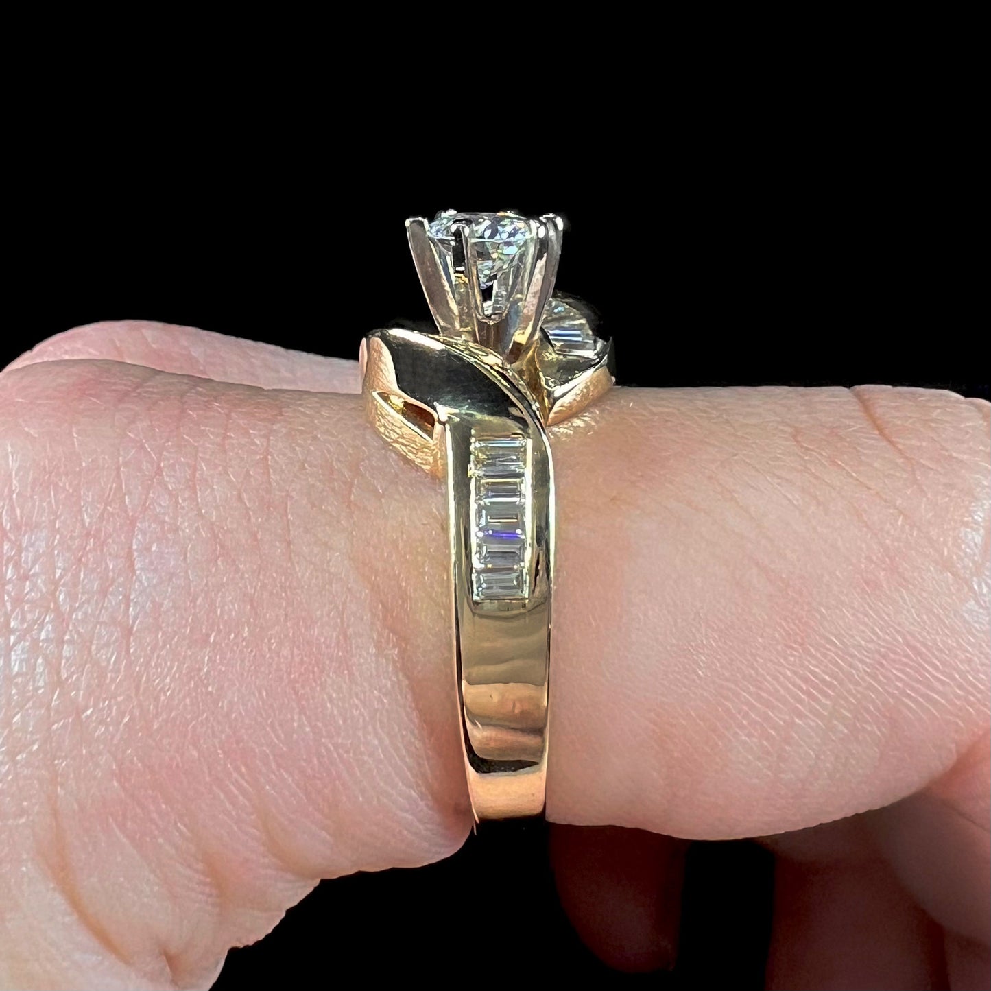 A ladies' yellow gold engagement ring set with a 0.77ct oval cut diamond and baguette cut diamond accents.