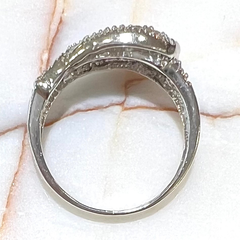 A white gold buckle ring pave set with round black and white diamonds.