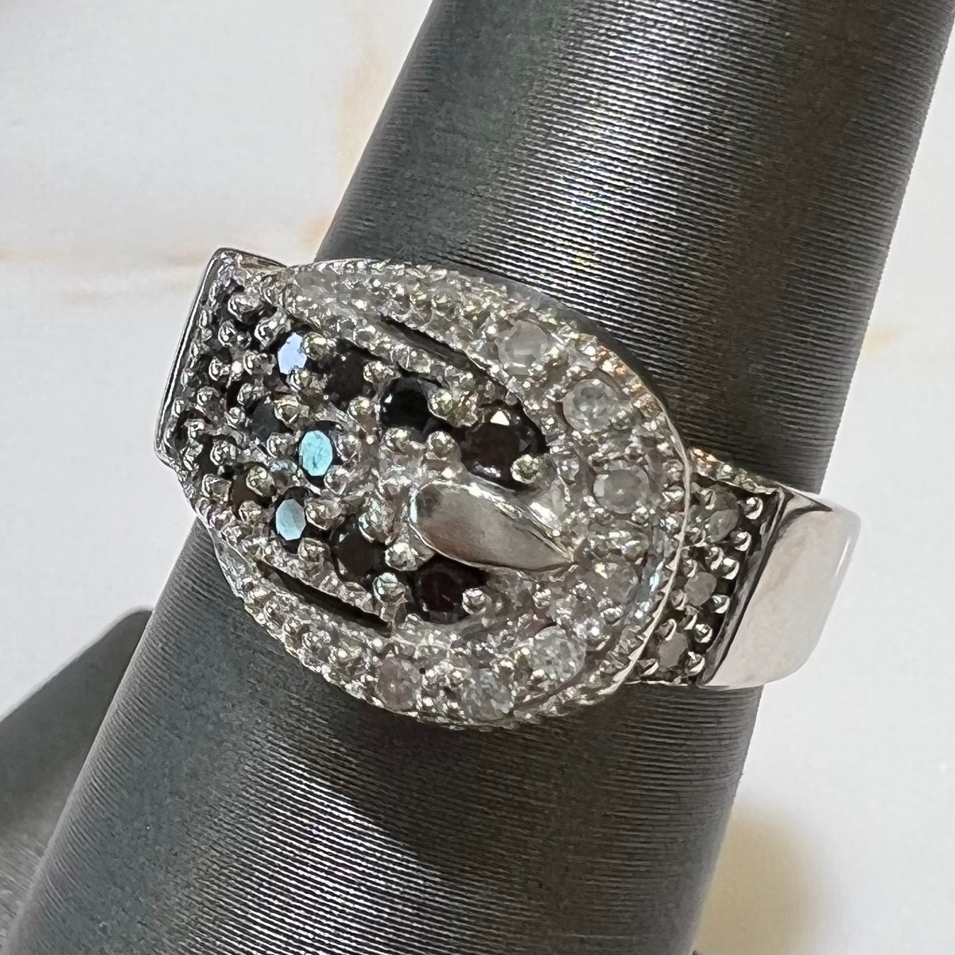 A white gold buckle ring pave set with round black and white diamonds.