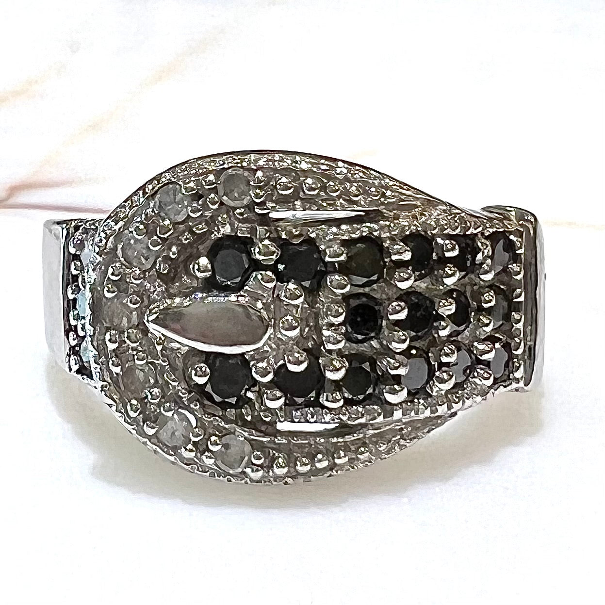 A white gold buckle ring pave set with round black and white diamonds.