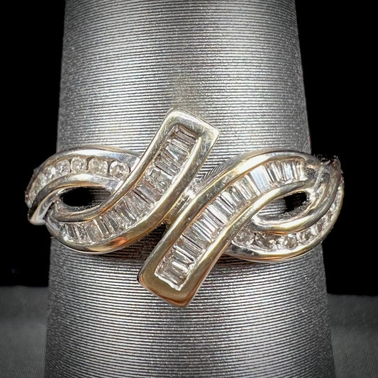 A ladies' white gold crisscross style ring channel set with round and baguette cut diamonds.