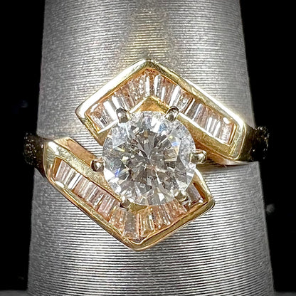 A gold diamond ring set with a round cut center stone with channel set baguette cut accent stones.