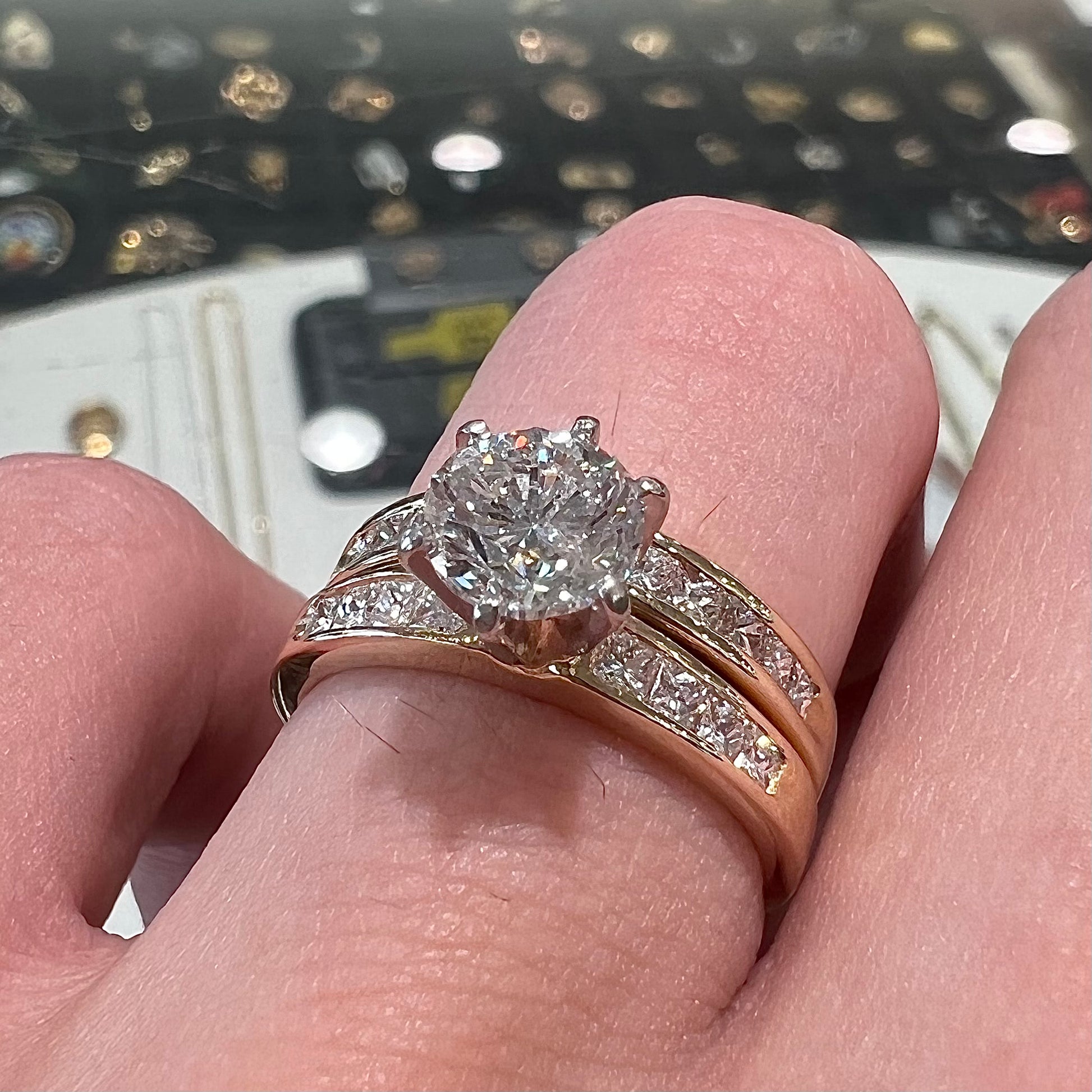 A diamond engagement and wedding ring set.  The center stone is a 1 carat round diamond, and the side stones are channel set princess cut diamonds.