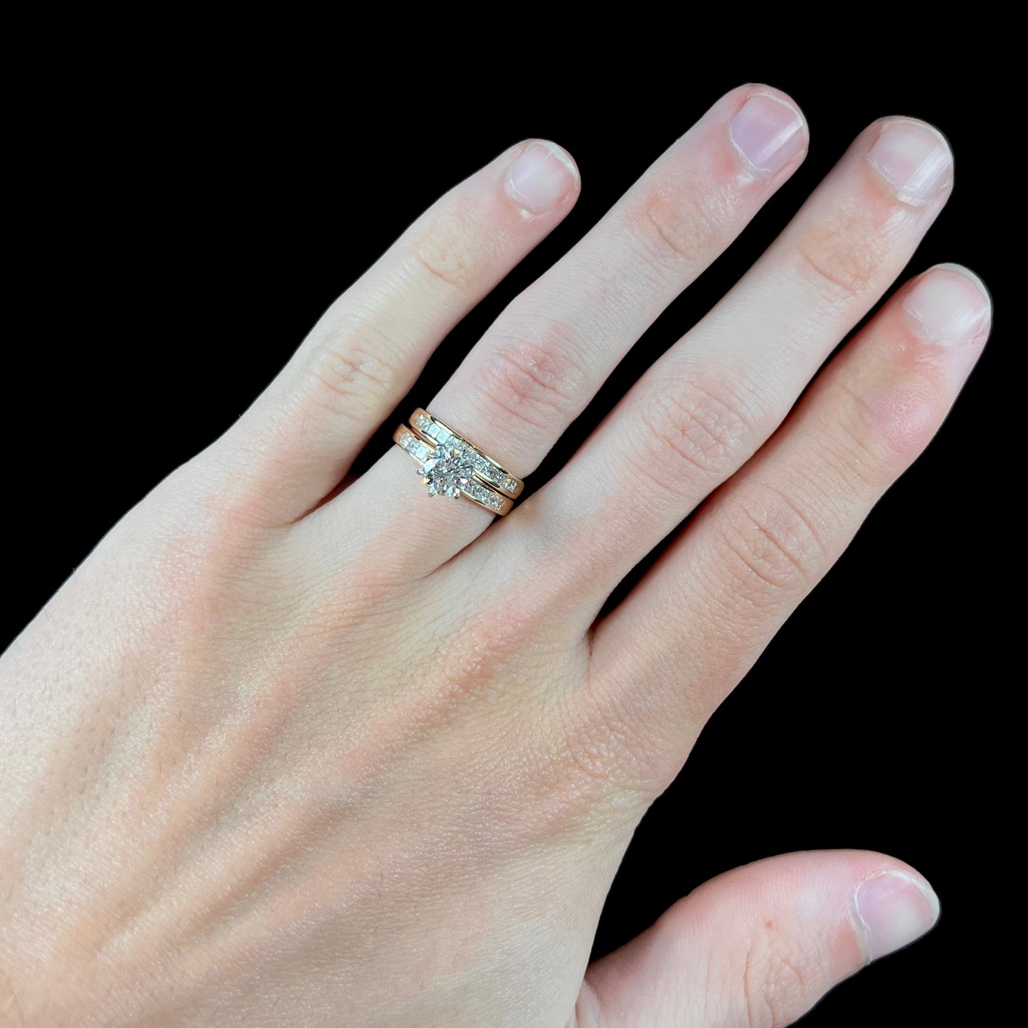 A diamond engagement and wedding ring set.  The center stone is a 1 carat round diamond, and the side stones are channel set princess cut diamonds.