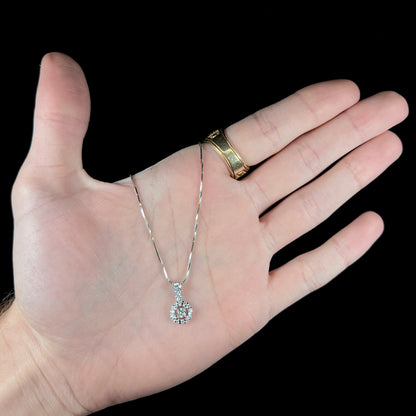 A ladies' diamond halo necklace with snake chain cast in platinum.