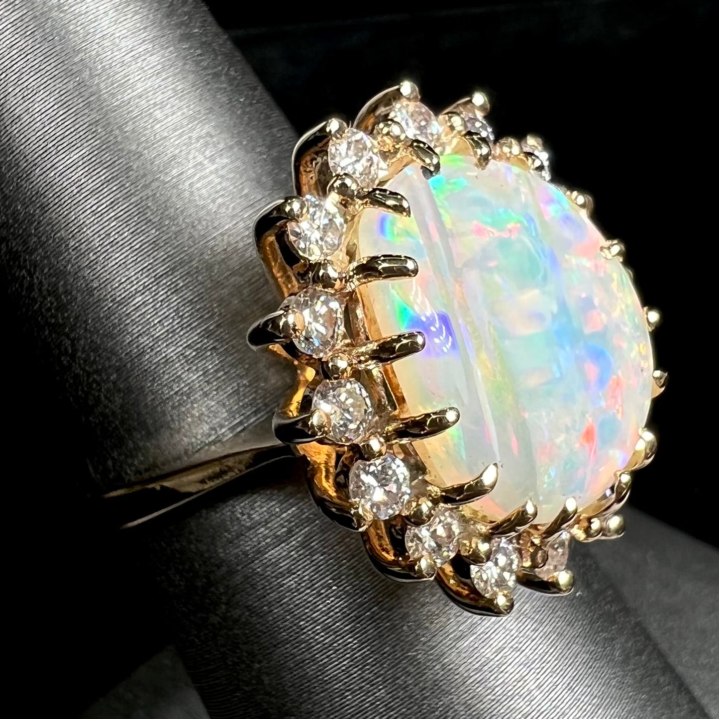 A ladies' diamond halo ring set with a Coober Pedy opalized seashell in yellow gold.