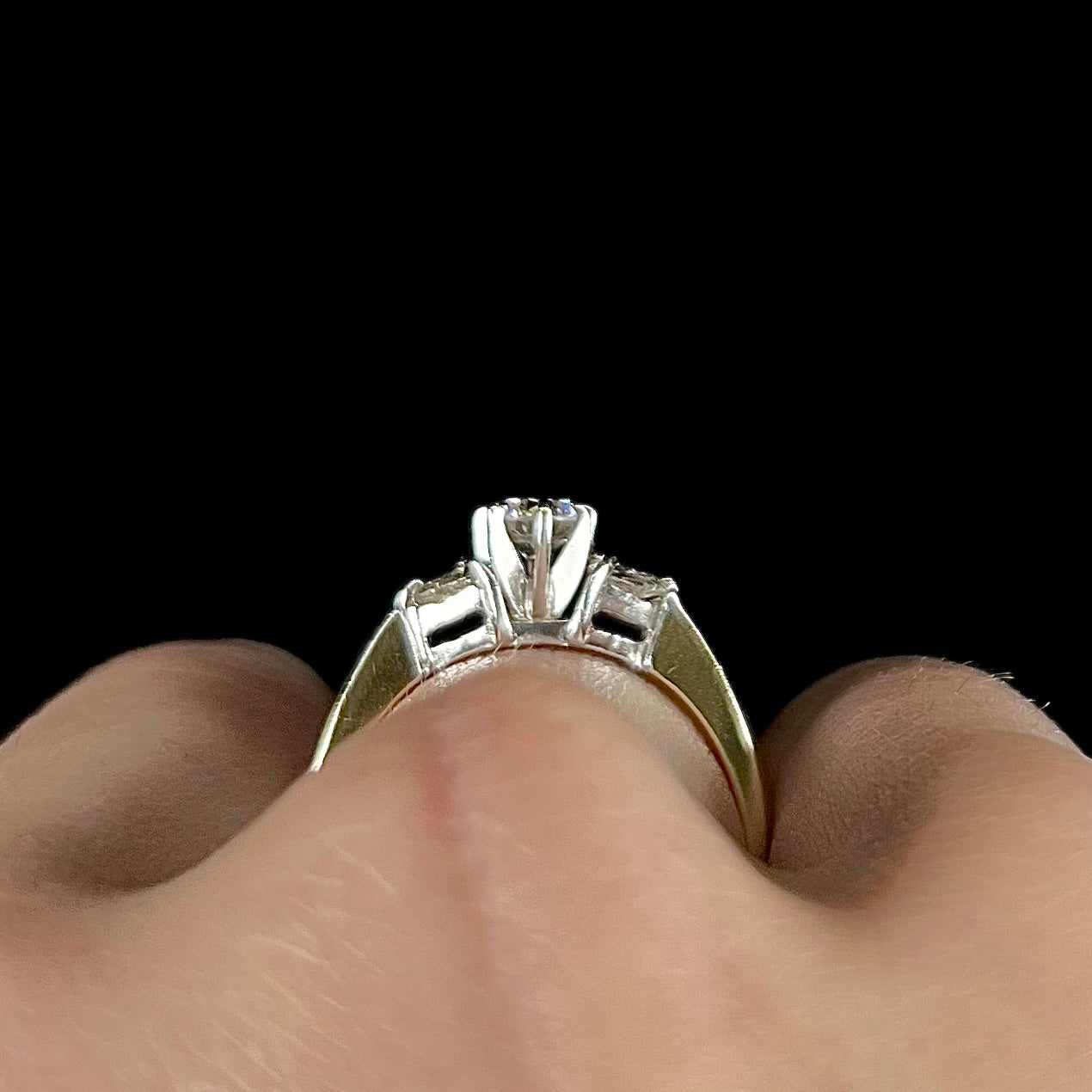 A ladies' three stone diamond ring.  The center diamond is a round brilliant cut, and the two accents are heart shaped diamonds.