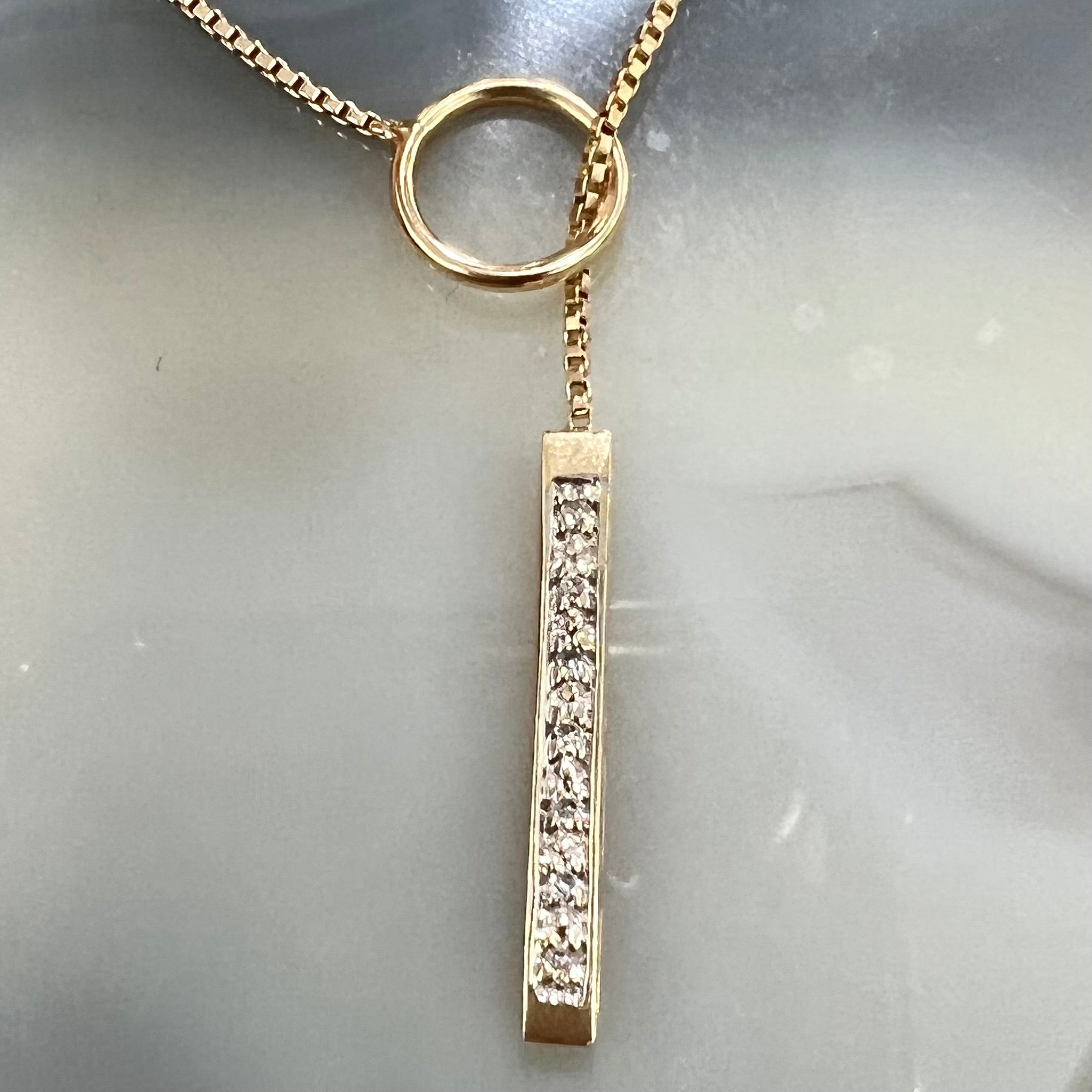 A yellow gold diamond lariat necklace on a 1mm wide box chain.  The lariat is double sided.