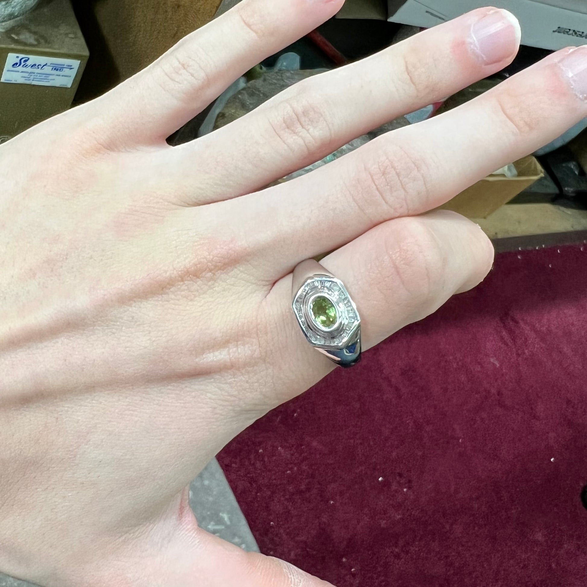 A sterling silver men's ring set with green peridot surrounded by baguette cut diamonds.