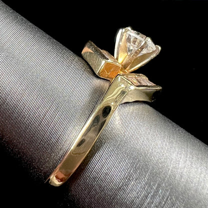A gold diamond ring set with a round cut center stone with channel set baguette cut accent stones.