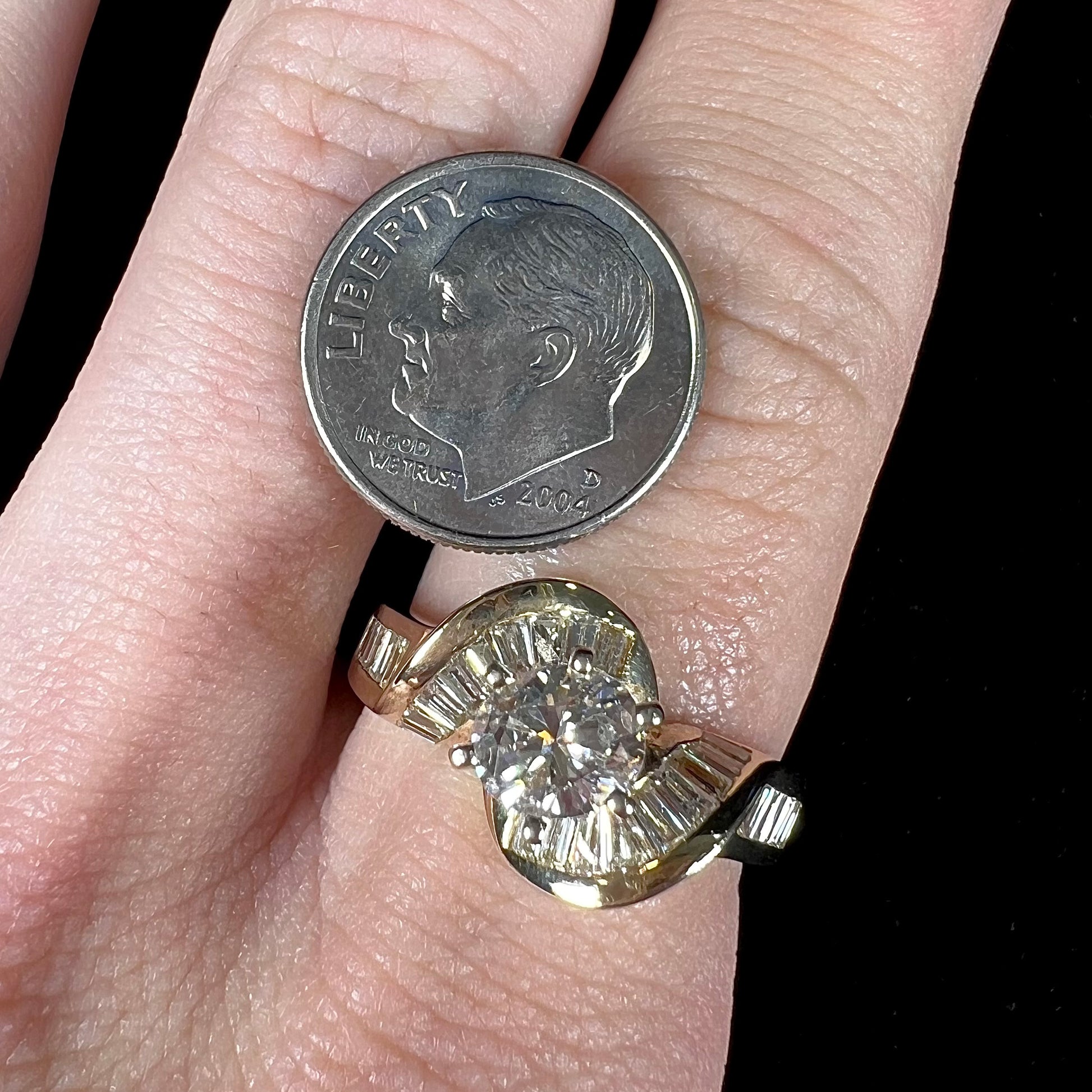 A ladies' yellow gold engagement ring set with a 0.77ct oval cut diamond and baguette cut diamond accents.