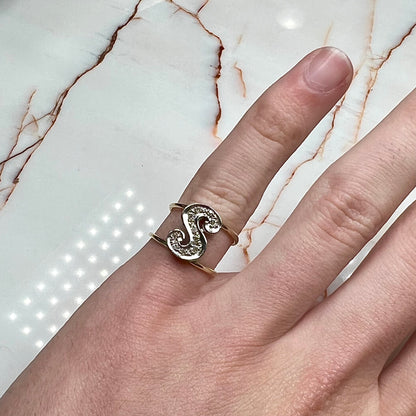 A two tone white and yellow gold initial ring of the letter "S" set with diamonds.
